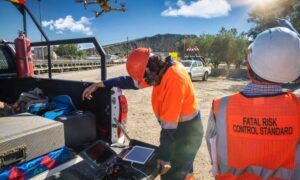 Drone surveyors on a construction site using UAV equipment with drone flying overhead