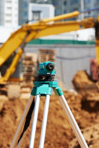 Commercial survey equipment bowling-green - ALTA SURVEY Kentucky Surveying instrument on tripod at a commercial construction site with excavation and buildings in the background to support accurate land surveys in Bowling Green