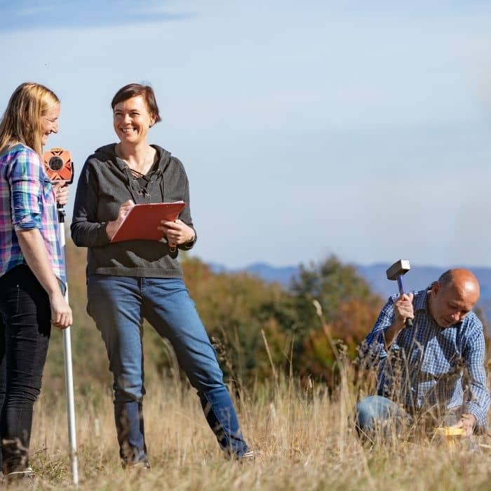 Land surveyors marking property boundaries and reviewing notes during an ALTA survey for buyers and investors
