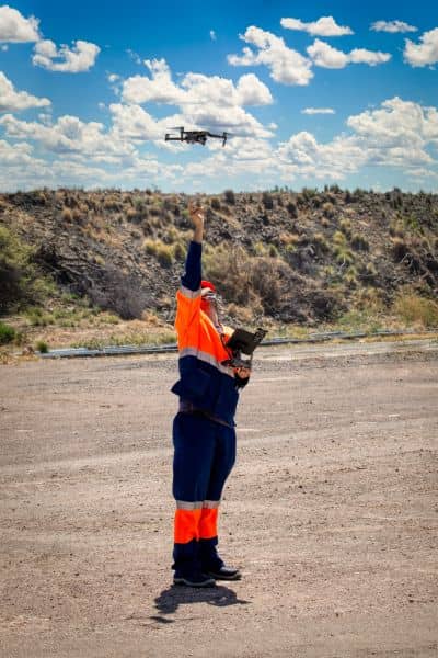 Surveyor in safety gear launching a drone for land surveying in an open area
