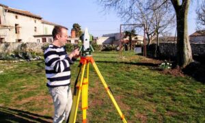 A licensed land surveyor measuring a home’s elevation to prepare a flood elevation certificate for lowering insurance costs