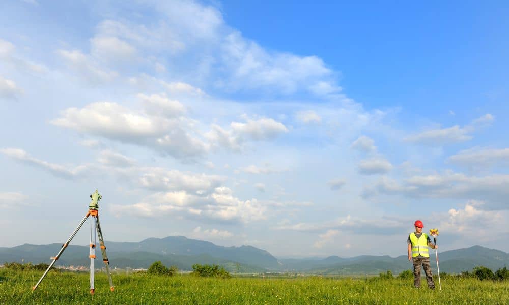 Land surveyor conducting a property survey in open karst terrain with rolling hills in the background
