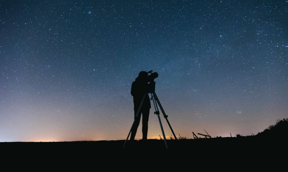 Geomagnetic storm boundary survey - ALTA SURVEY Kentucky Land surveyor using tripod equipment under a starry night sky showing how a geomagnetic storm can affect GNSS accuracy during a boundary survey