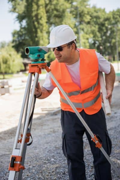Land surveyor verifying elevation data - ALTA SURVEY Kentucky Licensed land surveyor using leveling equipment to verify accurate elevation data for an elevation certificate after heavy rain