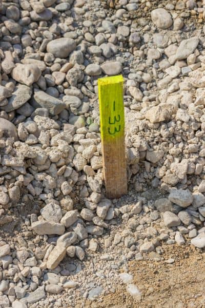 A close-up view of a construction staking survey marker placed in the ground to show precise layout and property line measurements