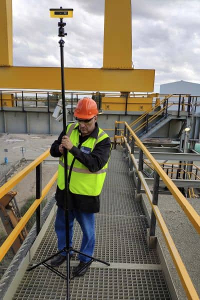 Surveyor using a GNSS RTK receiver to verify data accuracy during a drone survey