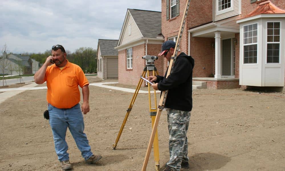 A construction staking survey being performed by surveyors in a residential neighborhood to ensure the home is built within the correct property lines