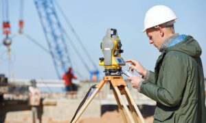 Licensed surveyor performing an ALTA land survey at an active industrial construction site