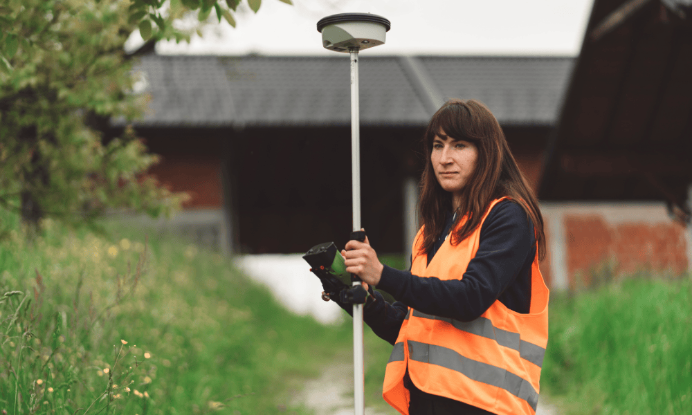 Surveyor using GNSS equipment during a home survey beside a residential property