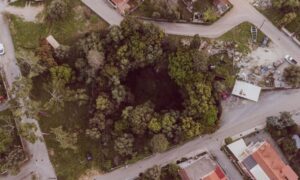Lidar mapping karst terrain site planning - ALTA SURVEY Kentucky Aerial view of a tree-lined depression near roads and buildings, illustrating how LiDAR mapping can help identify potential sinkhole areas during karst site planning